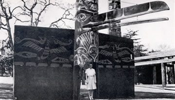 Nuxalk House Frontal Pole and Nuu-chah-nulth (Ahousaht) Ceremonial Screen with person in the doorway