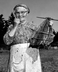 Agnes George montrant du saumon qu’elle vient de sécher. Mme George naquit dans l’Ancienne Réserve songhees et fut une des dernières personnes à parler couramment le lukwungen (lekügén), un dialecte que les linguistes appellent le salish des détroits du nord.